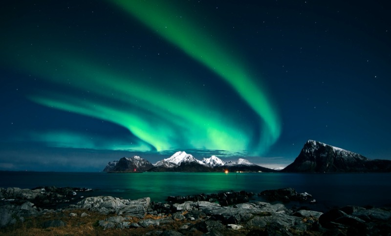 The aurora borealis in green ribbons above snow-covered peaks